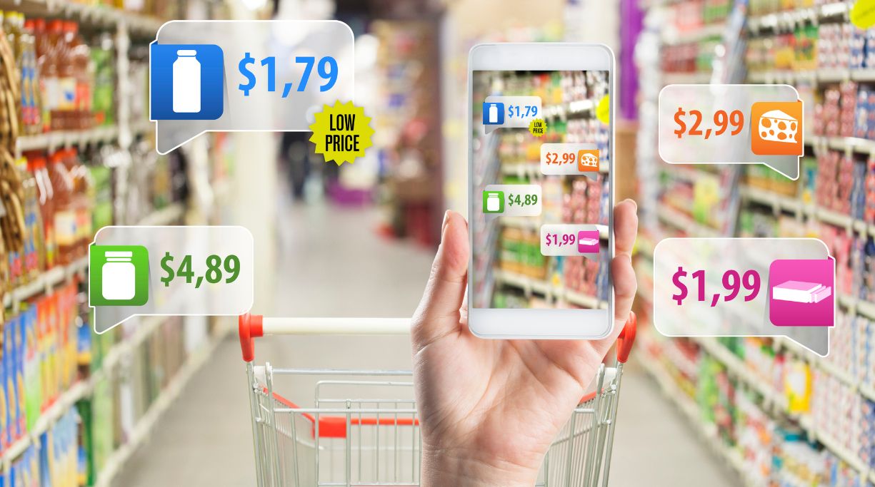 Image of a person holding a phone with various prices for various products on the screen in a grocery store aisle